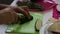 A man takes a cucumber from a plate, and starts cutting it on a cutting board.