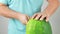 A man takes off a watermelon hat. A man cuts a watermelon in a circle and cuts a watermelon