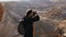 Man takes photos of amazing desert landscape. European male tourist with camera at massive mountain view. Israel 4K.