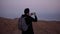 Man takes photos of amazing violet sky panorama. Slow motion. Excited tourist makes smartphone video of dusk mountains.