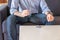 man takes pills drinks glass of water and is sitting on the sofa