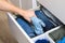 Man takes trousers folded by the method of Marie Kondo. Vertical storage of clothes in chest of drawers. Organization of