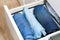 Man takes trousers folded by the method of Marie Kondo. Vertical storage of clothes in chest of drawers. Organization of