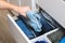 Man takes trousers folded by the method of Marie Kondo. Vertical storage of clothes in chest of drawers. Organization of storage.