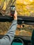 Man takes a vertical video on a mobile phone from the car on the road in the autumn beautiful forest