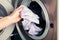Man taking color clothes from washing machine. A drum of washing machine full of dirty laundry in the bathroom