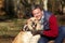 Man Taking Dog On Walk Through Autumn Woods