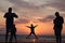 Man taking a photo of his son jumping into the sunset by the ocean sea side in France silouette