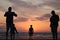 Man taking a photo of his son jumping into the sunset by the ocean sea side in France silouette