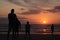 Man taking a photo of his son jumping into the sunset by the ocean sea side in France silouette