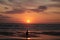 Man taking a photo of his son jumping into the sunset by the ocean sea side in France silouette