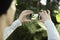 Man taking photo picture by mobile phone in a travel journey, green plants in a park. Focused on phone screen