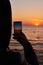 Man taking photos of sunset with mobile phone. Traveler young man is shooting video and photo of beautiful sunrise landscape on