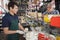 Man Talking With Salesman Slicing Cheese In Shop