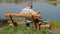 Man talking on smart phone on the bench near river