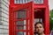 A man is talking in a typical London phone booth