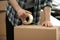 Man taping cardboard box indoors, closeup view