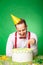 Man tasting birthday cake on green background