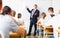 Man teacher with notebook is giving interesting lecture for students in classroom