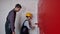 A man teaches his son how to paint walls