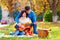 Man teaching girl play a guitar on autumn picnic