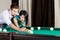 Man teaching girl to play billiard