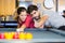 Man teaching girl to play billiards