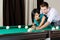 Man teaching girl to play billiards