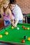 Man teaching his girlfriend how to play pool