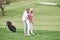 Man teaching woman to play golf at the sport field with equipment behind