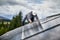 Man technician mounting photovoltaic solar panels on roof of house with help of hex key.