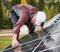 Man technician mounting photovoltaic solar panels on roof of house with help of hex key.