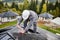 Man technician mounting photovoltaic solar panels on roof of house with help of hex key.