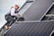 Man technician mounting photovoltaic solar panels on roof of house with help of hex key.