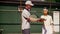 A man tennis coach teaches his ward to hold the racket correctly and master the hitting technique. A young girl athlete