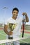 Man on tennis court Holding Trophy