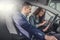 Man testing a car in the sales shop smiles looking into a tablet in the hands of the female car dealer showing technicalities