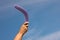 Man throwing boomerang against blue sky, closeup. Space for text