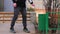 A man throws garbage, a white napkin in the trash on the street at the entrance of the house