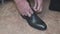 Man ties his shiney new black leather business shoes