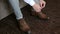 Man ties up shoelaces on brown leather shoes, close-up.