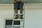 Man with tools standing on ladder at roofline