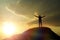 A man at the top of the mountain, raising his hands up against the backdrop of the glare of the sun.