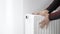 A man touches the cold radiator of a home heater and increases the heating power