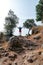 Man Tourism traveler hiker with a backpack standing on the rock hands up enjoi nature with olive trees, travel Hiking adventure