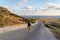 Man tourist with backpack walks down mountain along asphalt road towards mediterranean sea in cyprus in area of Agios