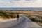 Man tourist with backpack walks down mountain along asphalt road towards mediterranean sea in cyprus in area of Agios