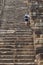 Man tourist climbs the high stair of ancient temple. Endless steps of ancient buddhist temple in Angkor Wat.