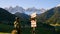 Man tourist looking at wooden pointer at the trail in Dolomites Alps near Santa Maddalena village. Male traveler looking