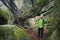 Man tourist meditating in sacred mystical place in the forest with huge moss covered rocks and gnarled wood. Calm down, feeling